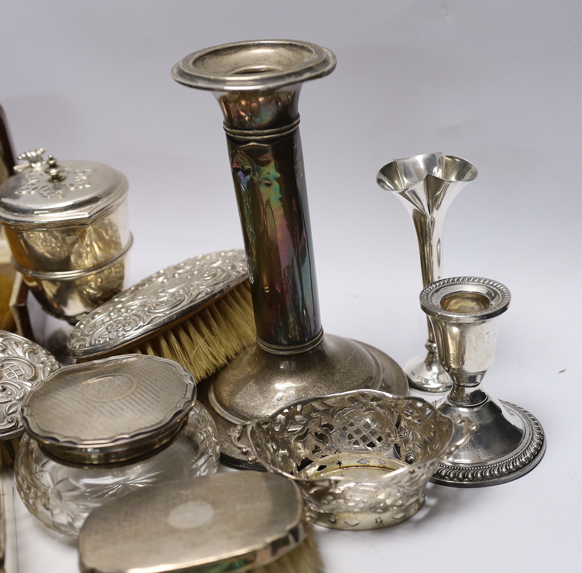 Sundry silver items including a pair of candlesticks, marks rubbed, handled magnifying glass, lidded vase, hand mirror, five brushes, cigarette box, trinket box, toilet jar and eleven other items including a novelty shoe